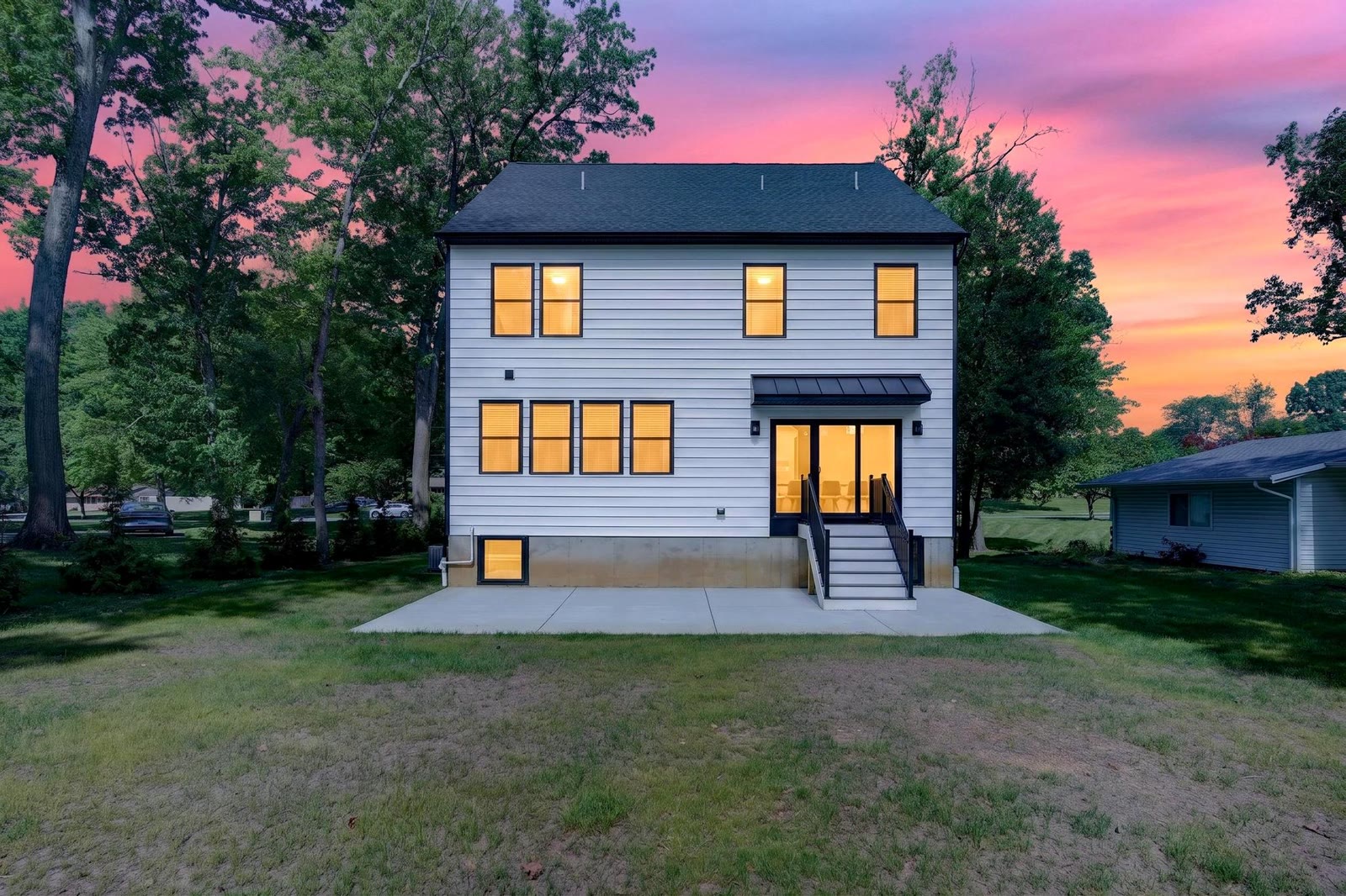 The back of the home at dusk, lit from inside